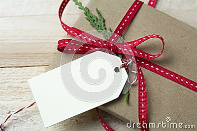 Gift box, wrapped in recycled paper, red bow and tag on wood bac Stock Photo