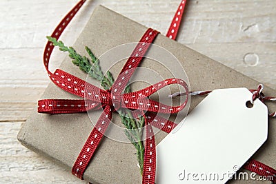 Gift box, wrapped in recycled paper, red bow and tag on wood bac Stock Photo