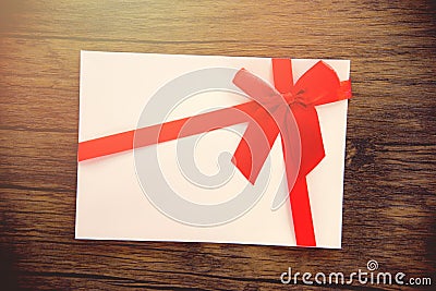 Gift card on wooden background Pink white Gift card decorated with red ribbon bow to Merry Christmas Holiday Happy new year or Stock Photo