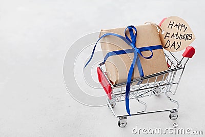 Gift or present box and notes Happy Fathers Day in shopping cart on light background Stock Photo