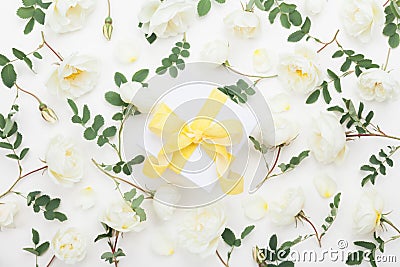 Gift or present box and pastel rose flowers decorated green leaves on white table top view. Flat lay style. Stock Photo