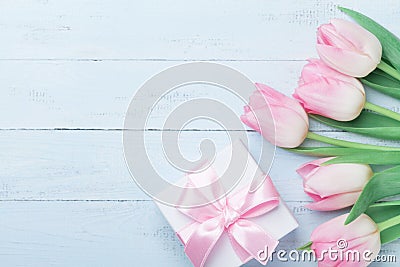 Gift or present box and pink tulip flowers on blue wooden table top view. Greeting card for Womans or Mothers Day. Flat lay. Stock Photo