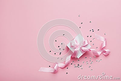 Gift or present box and sequins on pink table top view. Flat lay. Birthday, wedding or christmas concept. Stock Photo