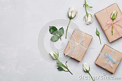 Gift or present box wrapped in kraft paper and rose flower on gray table from above. Flat lay styling. Copy space for text. Stock Photo