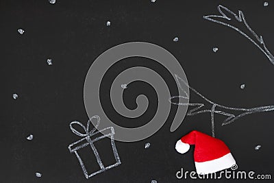 Gift and reindeer antlers drawn with chalk on blackboard with Santa Claus hat, creative concept christmas background Stock Photo