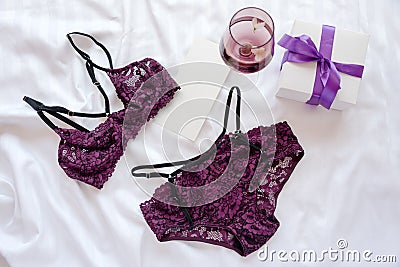 Gift, shopping and fashion concept. Set of glamorous stylish lace lingerie on bed with giftbox and wineglass on Stock Photo