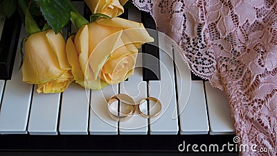 Gift to the beloved woman, yellow roses lie on the piano with engagement ring on pink lace,lingerie, underwear on the wedding day Stock Photo