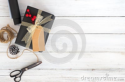 Hand crafted Christmas present gift box and tools on white wooden background. Stock Photo