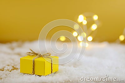 Gift in yellow wrapping paper on a gold background. Stock Photo