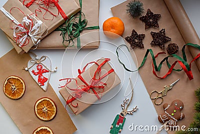 Gifts in craft paper, tied with red and green ribbon, surrounded by Christmas trifles Stock Photo