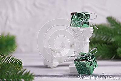 Gifts in foil wrapped on a decorative column on a white wooden background. Stock Photo