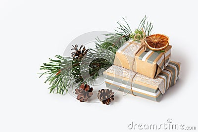 Gifts packed in kraft paper on a white isolated background. Pine branches and cones, dried oranges. Copy space. Christmas Stock Photo