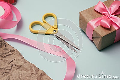 Gifts wrapping process. Decorative paper, silk ribbons, gift boxes, scissors. Light blue background. Stock Photo
