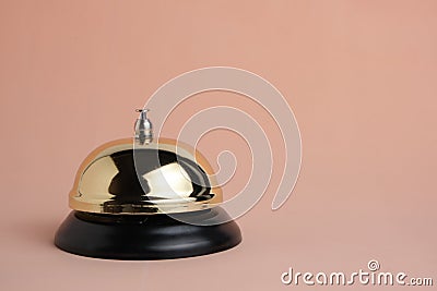 Gilded bell hotel service on pastel beige background, isolated.Conceptual hotel, travel and recreation Stock Photo