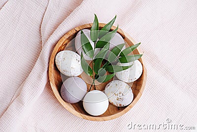 Gilded eggs along with regular ones in a wooden bowl over pink checkered cloth Stock Photo