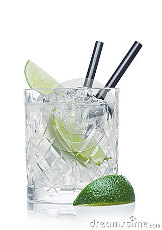 Gimlet cocktail in crystal glass with ice cubes and straw and lime slices on white Stock Photo