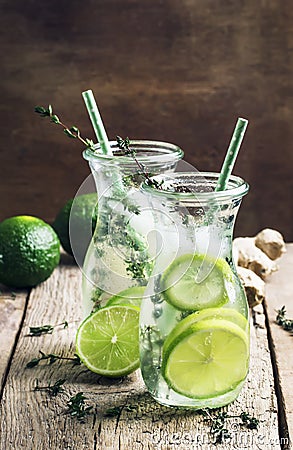 Ginger ale with lime, herbal cold summer drink with thyme and ice, vintage wooden table background, selective focus Stock Photo