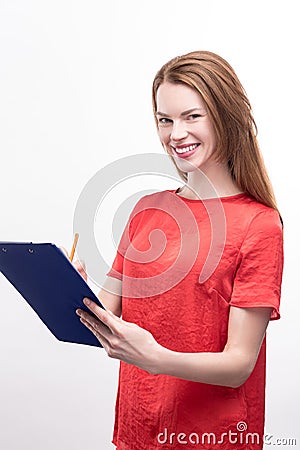 Ginger-haired woman filling in form on sheet holder Stock Photo
