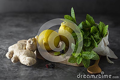 Ginger, lemons and mint leaves on dark background. Ginger tea, drink ingredients, cold and autumn time Stock Photo