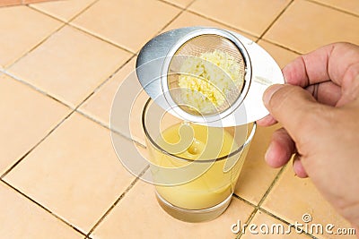 Ginger roots juice being sieved after extraction Stock Photo