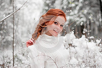 Ginger sweet girl in white sweater in winter forest. Snow december in park. Portrait. Christmas cute time. Stock Photo