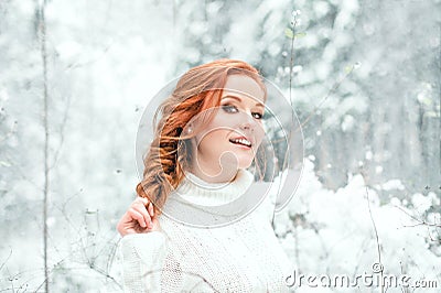 Ginger sweet girl in white sweater in winter forest. Snow december in park. Portrait. Christmas cute time. Stock Photo