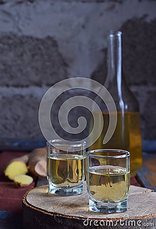 Ginger tincture or ale on wooden background. Spice yellow liqueur in a glass. Homemade Alcohol drink. Rustic style Stock Photo