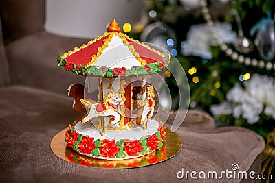 Gingerbread carousel in front of defocused lights of Chrismtas decorated fir tree. Holiday sweets. New Year and Christmas theme. F Stock Photo