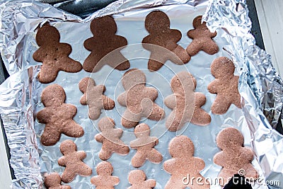 Gingerbread mans on foil and baking sheet Stock Photo