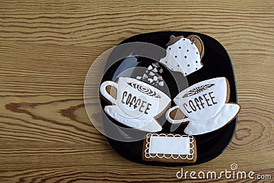 Gingerbreads in the form of cups with coffee, napkin and coffee pot. Gingerbread is on a black plate. Stock Photo