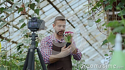 Giovane fiorista sorridente dell'uomo di blogger nel blog video di conversazione e di registrazione del fiore della tenuta del gr stock footage Giovane fiorista sorridente dell'uomo di blogger nel blog video di conversazione e di registrazione del fiore della tenuta del gr stock footage