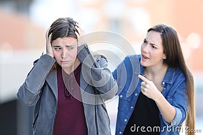 Girl accusing her sad friend in the street Stock Photo