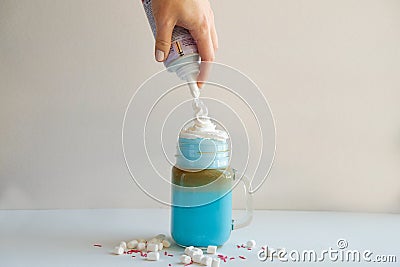 Girl is adding cream in cup of colored blue milk. Milk shake, cocktaill, frappuccino. Unicorn coffee Stock Photo