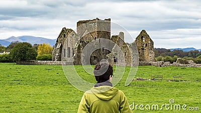 Girl admiring the ruins of a castle situated near a lake in Ireland highlands Stock Photo