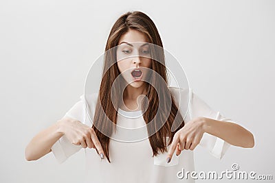 Girl is amazed standing on transparent floor. Portrait of overwhelmed attractive woman pointing down with index fingers Stock Photo