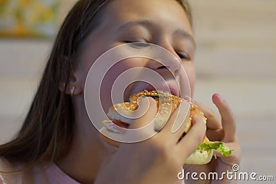 Girl with appetite eats delicious hamburger. child bites off large piece of sandwich Stock Photo