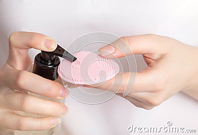 A girl applies a cleansing tonic to a silicone facial brush, close-up. Hygiene and skin care concept, treatment Stock Photo