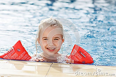 The girl in the arm ruffles in the pool smiling Stock Photo