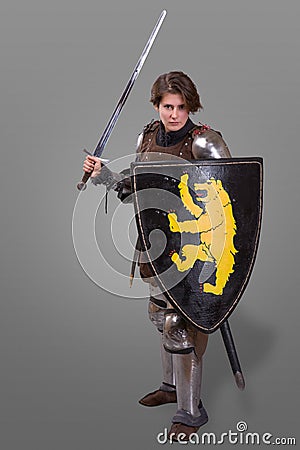 Girl in armor with a sword knight wuth shield over grey background Stock Photo
