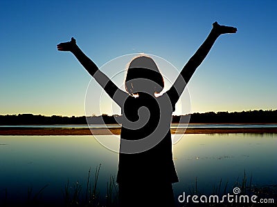 Girl with Arms Raised by Lake Stock Photo