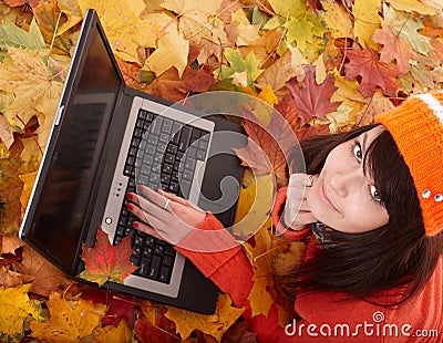 Girl in autumn orange foliage with laptop. Stock Photo
