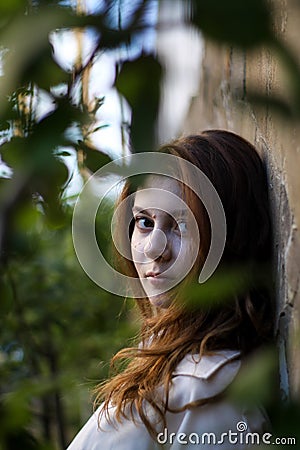 girl on a background of a brick wall with tree leaves. a combination of nature and construction. alive and not alive. Stock Photo