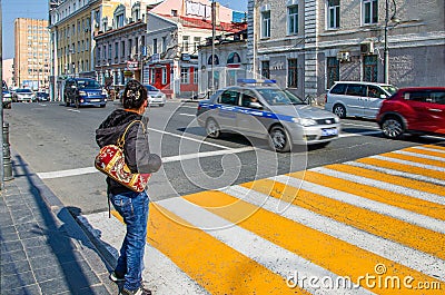 Girl with a backpack expects to cross the road near a pedestrian crossing Editorial Stock Photo