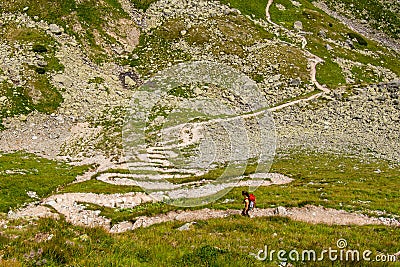 Girl backpacker on zigzagged hiking path serpentines, Austria mountains, Alps Editorial Stock Photo