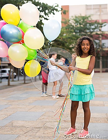 Girl with balloons standing outdoors Stock Photo