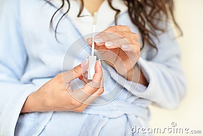 The girl in the bathroom, in a blue robe makes makeup, woman holds a brush for eyelashes, mascara, serum for hair, eyelashes, Stock Photo