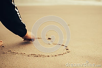 Girl at the beach drawing hearts on a sand. Stock Photo