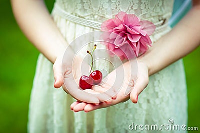 Girl in a beautiful dress is holding the berries of ripe sweet cherries Stock Photo