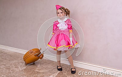 A girl in a beautiful fashionable dress with a child's suitcase. Stock Photo