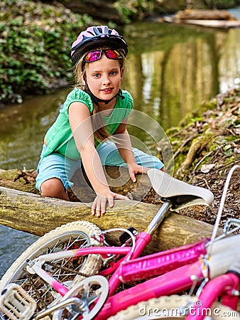 Girl on bicycle fording throught water onto log in park. Stock Photo